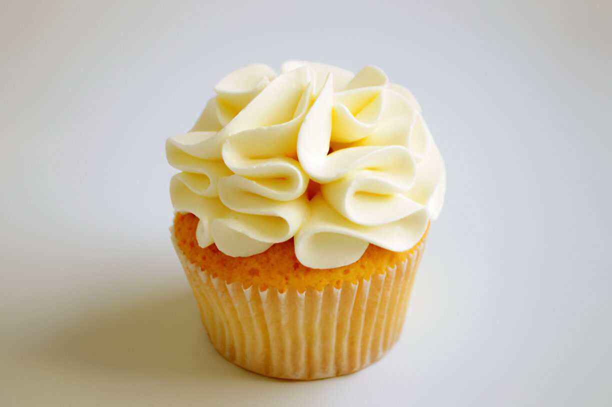 A delicious vanilla cupcake with fluffy white frosting on top