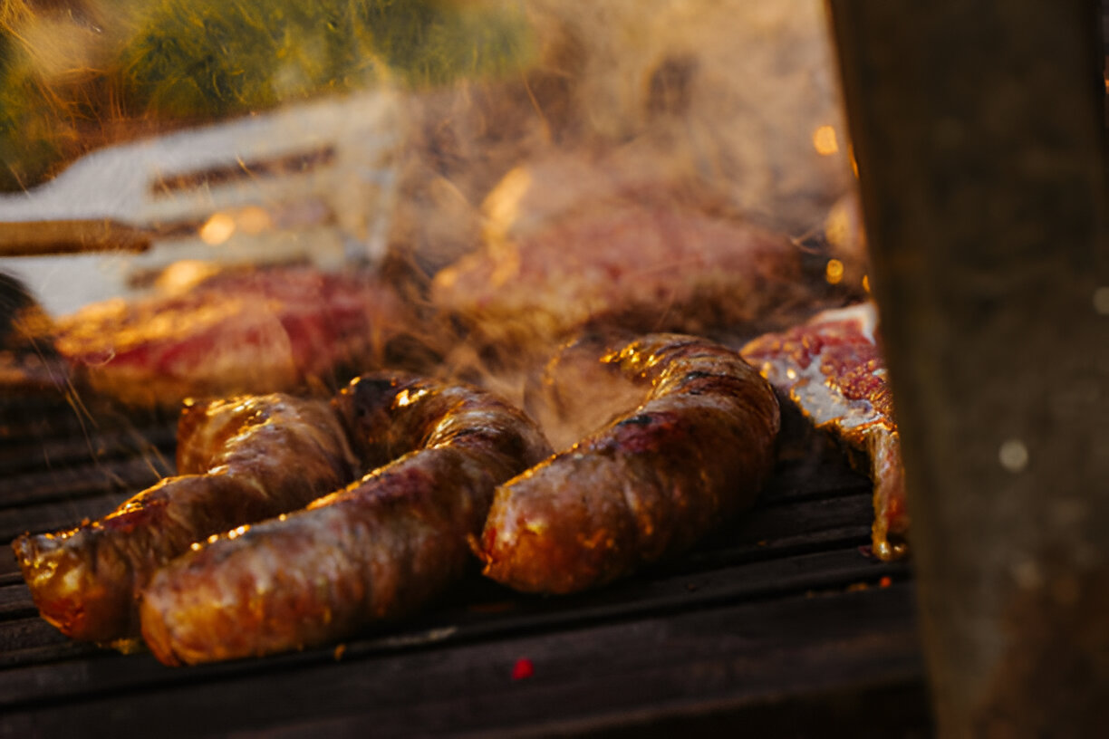 A freshly roasted piece of meat on a wooden cutting board, accompanied by a sharp knife and a carving fork.
