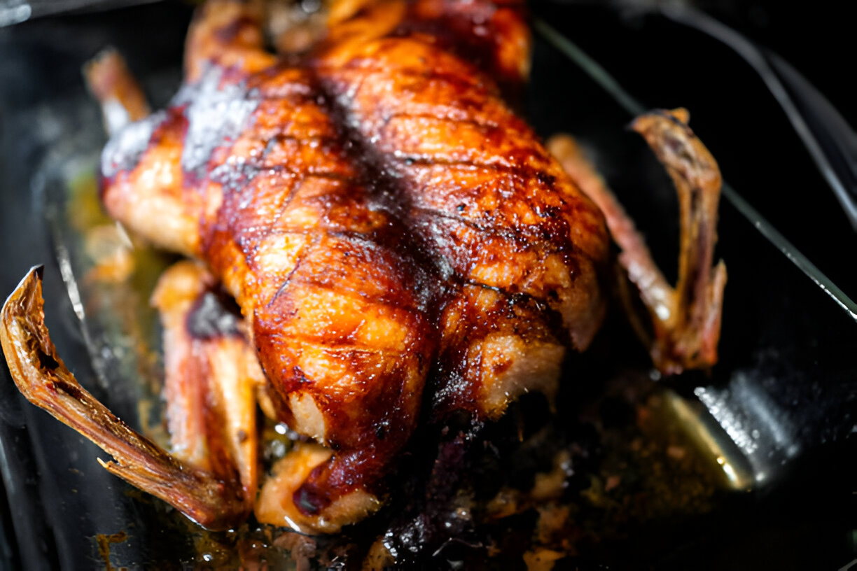 A beautifully roasted whole chicken with crispy skin, resting in a glass dish.