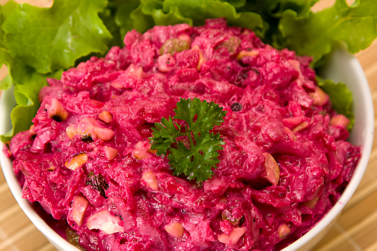 A vibrant pink beet salad garnished with fresh cilantro, served on a bed of lettuce leaves.