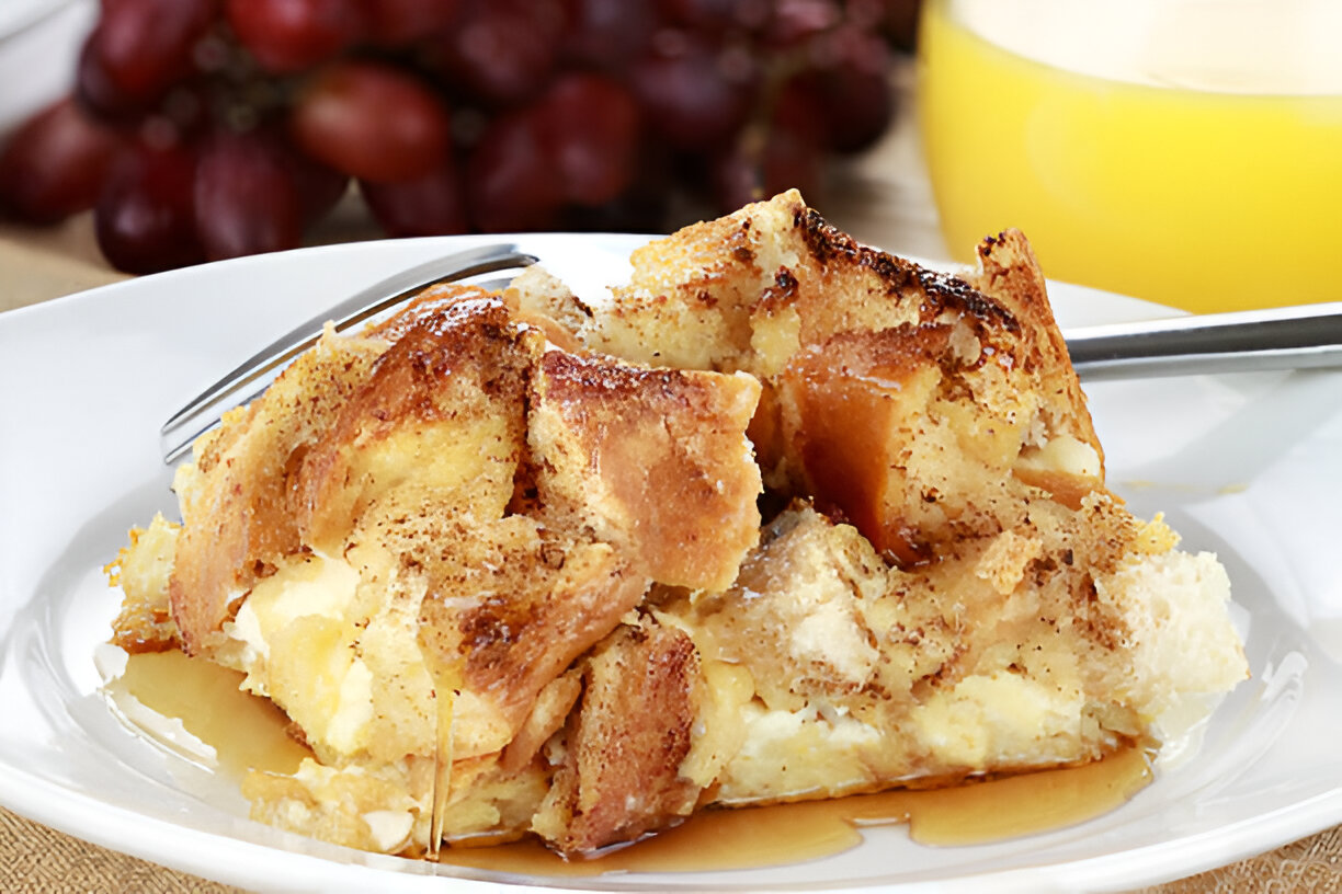 Delicious bread pudding topped with syrup, served on a white plate.