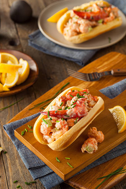 A delicious seafood roll topped with lobster and shrimp served on a wooden board with lemon slices in the background.