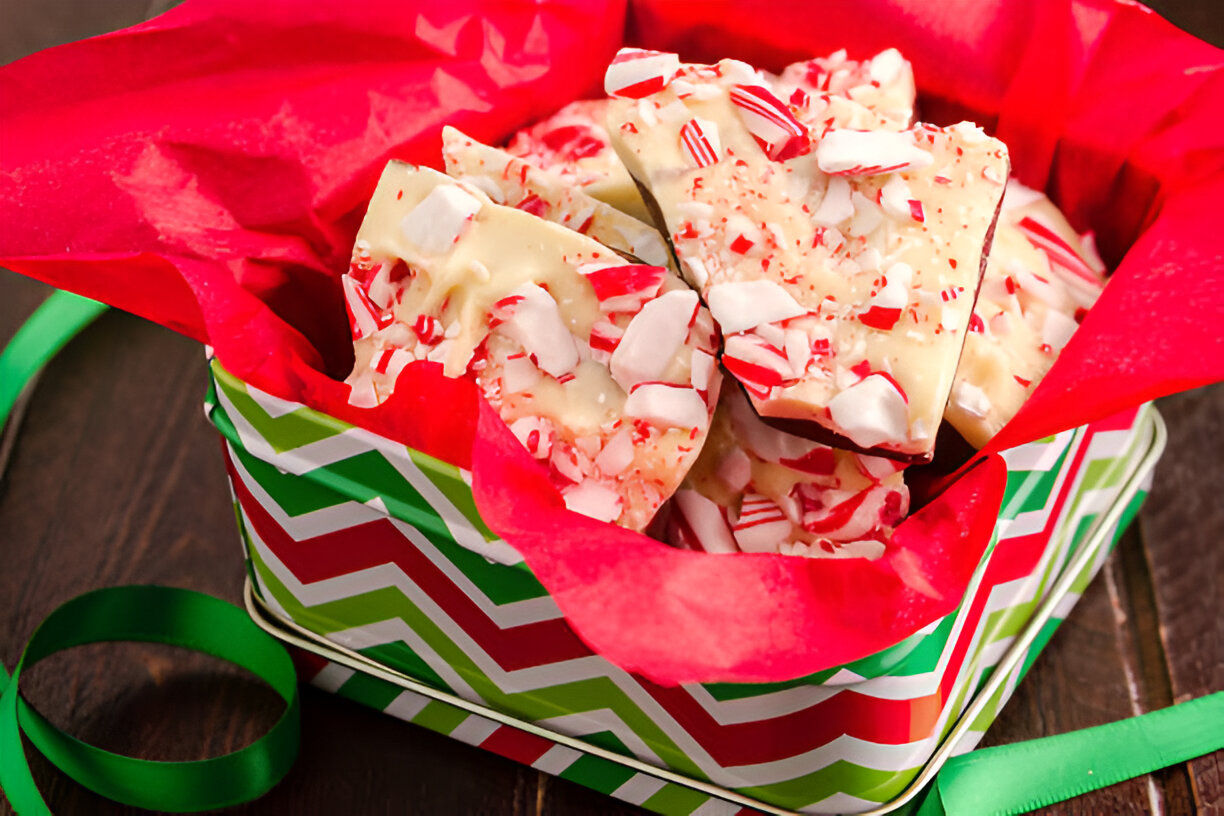 A festive gift box filled with white chocolate peppermint bark wrapped in red tissue paper.