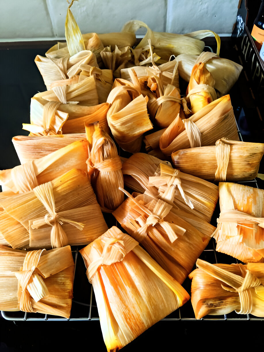 A collection of tamales wrapped in corn husks, neatly arranged on a cooling rack.