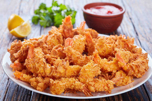 Plate of crispy fried shrimps served with lemon wedges and dipping sauce