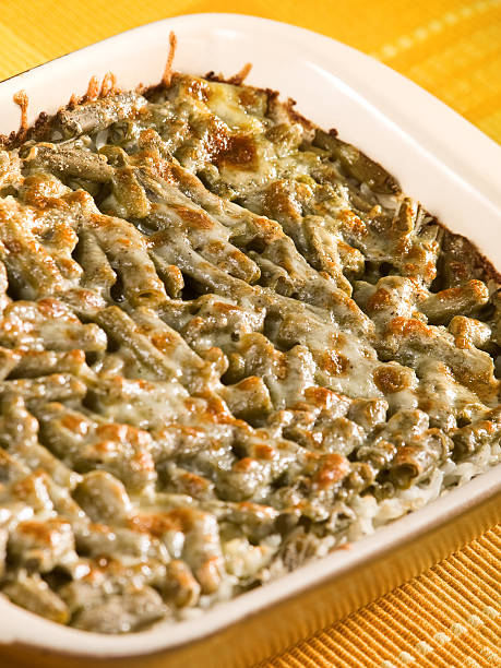 A close-up of a baked casserole featuring a creamy green vegetable topping over a bed of rice.