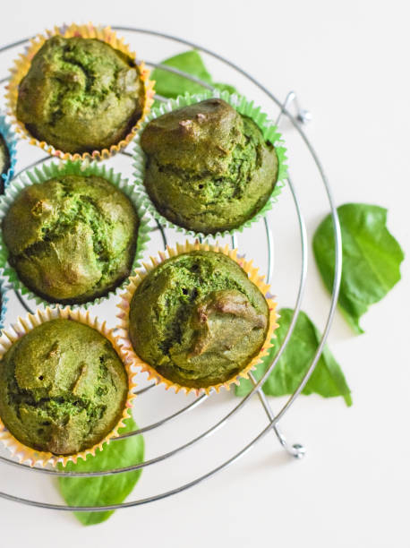 A round cooling rack with green spinach muffins topped with vibrant green leaves.