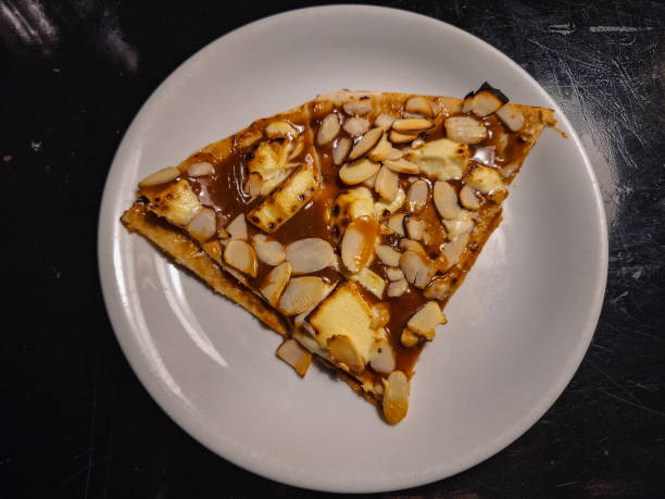 A slice of dessert topped with almonds on a white plate.