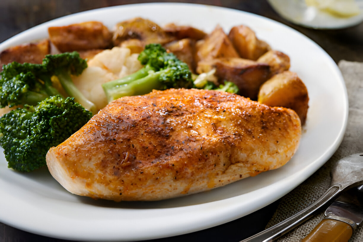 A plate of roasted chicken breast served with broccoli, cauliflower, and golden-brown roasted potatoes.
