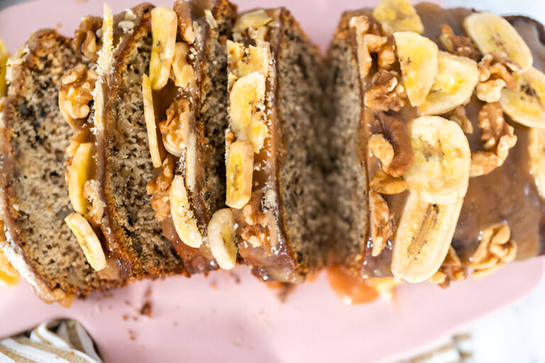 Sliced banana bread topped with caramel and sliced bananas, displaying a moist texture and nutty toppings.
