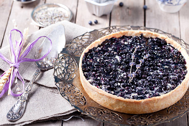 A delicious blueberry tart on an ornate silver platter, surrounded by vintage utensils and decorations.