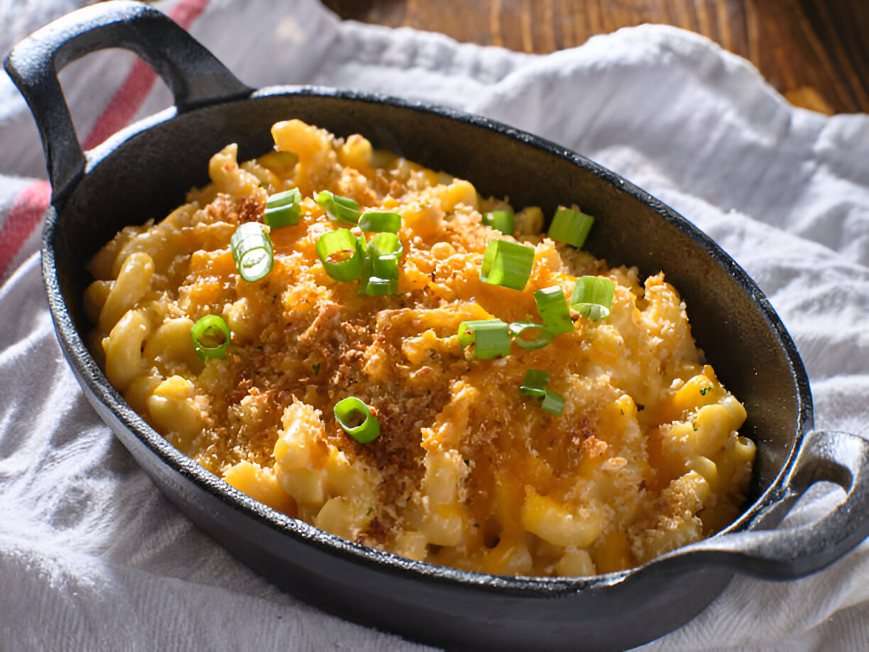 A delicious serving of macaroni and cheese topped with green onions in a cast iron skillet.