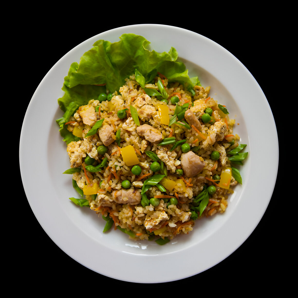 A plate of colorful fried rice with chicken, green peas, carrots, and yellow bell pepper, garnished with lettuce leaves.