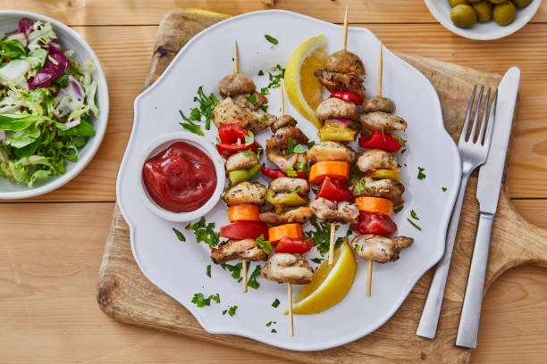 Grilled chicken and vegetable skewers served with lemon slices and a side salad.