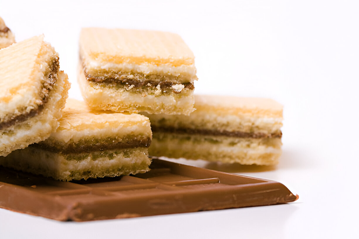 Layered wafer biscuits with a chocolate bar in the background