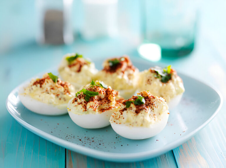 A plate of deliciously garnished deviled eggs topped with spices and herbs.