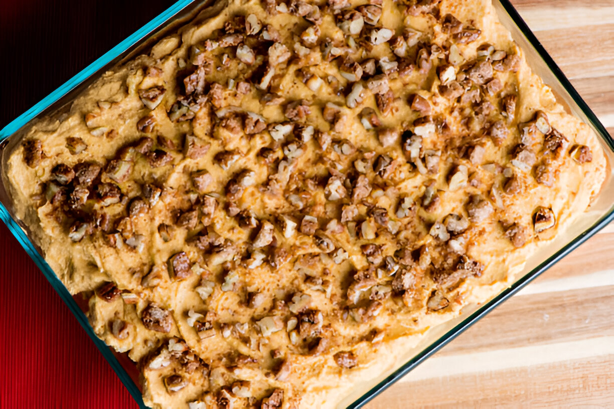 A rectangular glass dish filled with a golden-brown baked dessert topped with chopped nuts.