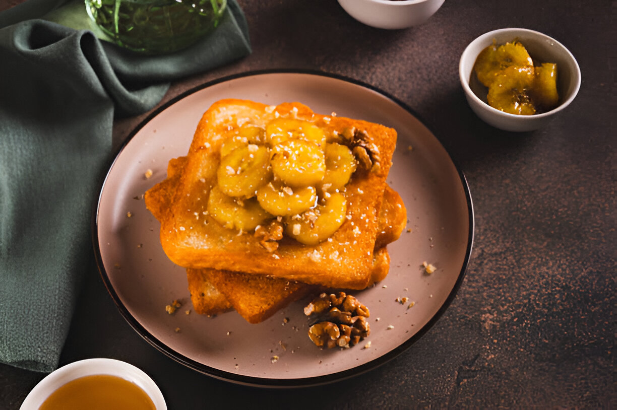Delicious French toast topped with bananas and walnuts on a plate.