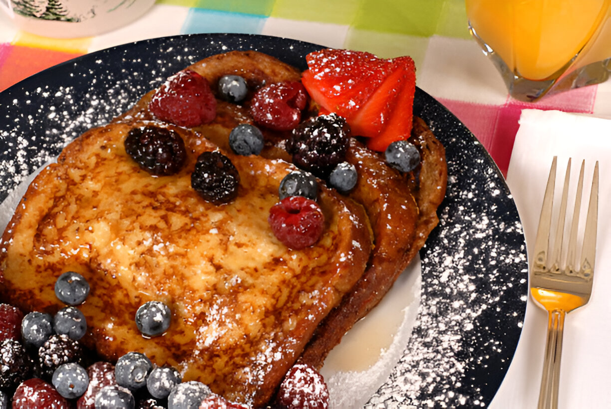 Delicious French toast topped with mixed berries and powdered sugar on a plate.