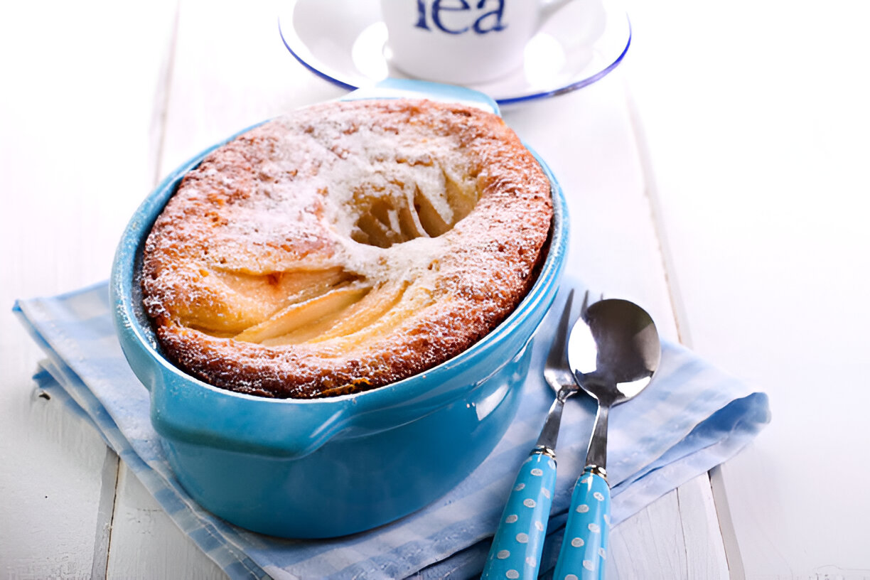 A freshly baked dessert in a blue dish, topped with powdered sugar on a light-colored napkin.