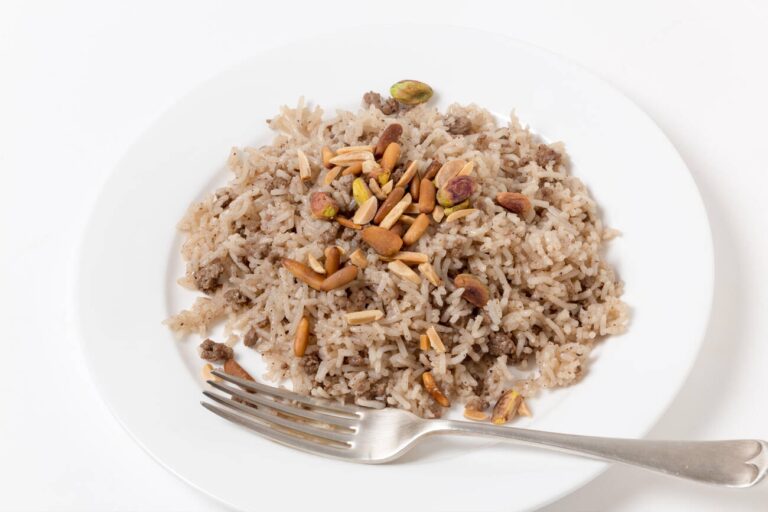 A plate of seasoned rice mixed with ground meat and garnished with toasted nuts.