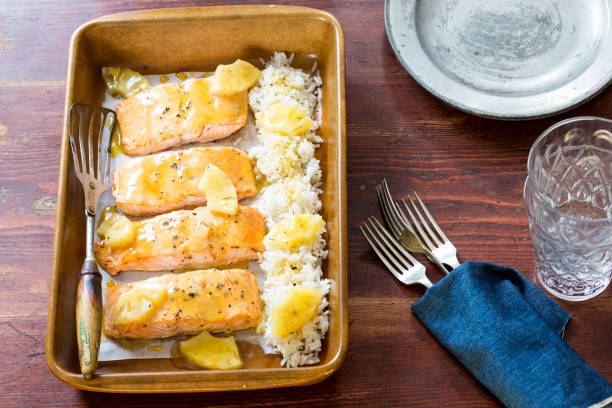Baked salmon fillets with lemon and rice in a serving dish on a wooden table