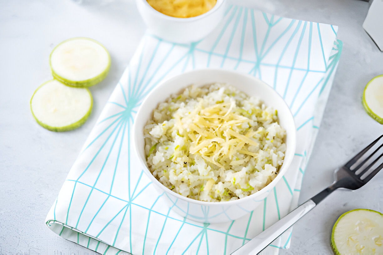 A bowl of rice with shredded cheese on top, placed on a patterned napkin next to lime slices.