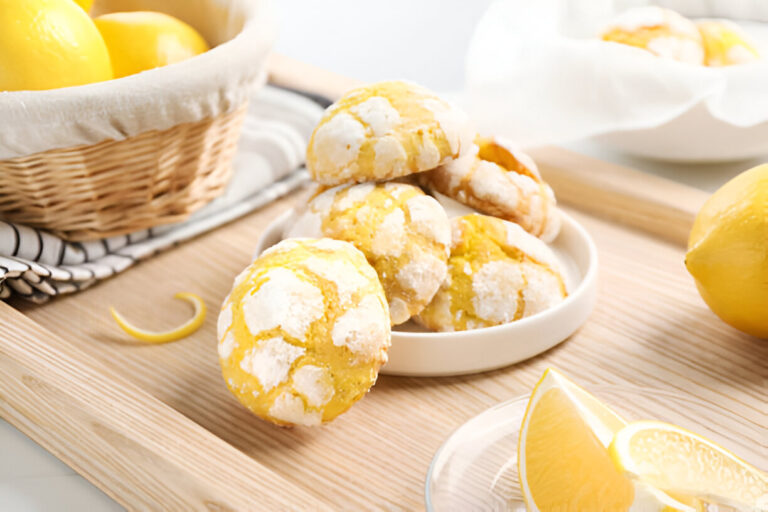 A plate of delicious lemon crinkle cookies with a basket of lemons in the background, on a wooden table.