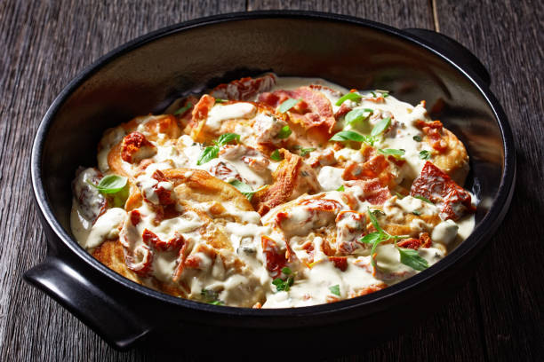 A delicious dish featuring baked potatoes topped with creamy sauce, crispy bacon, and herbs served in a black dish.