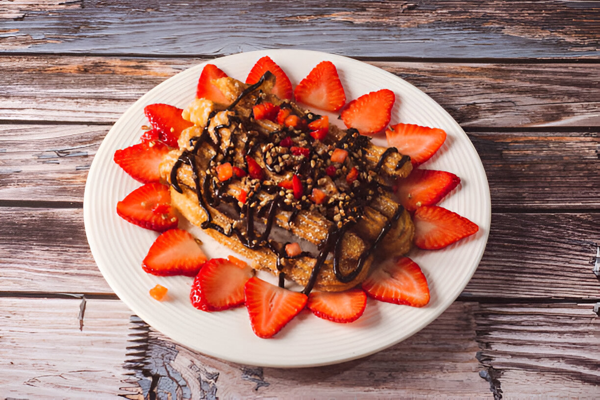 A plate of delicious dessert featuring churros topped with chocolate sauce and fresh strawberries.