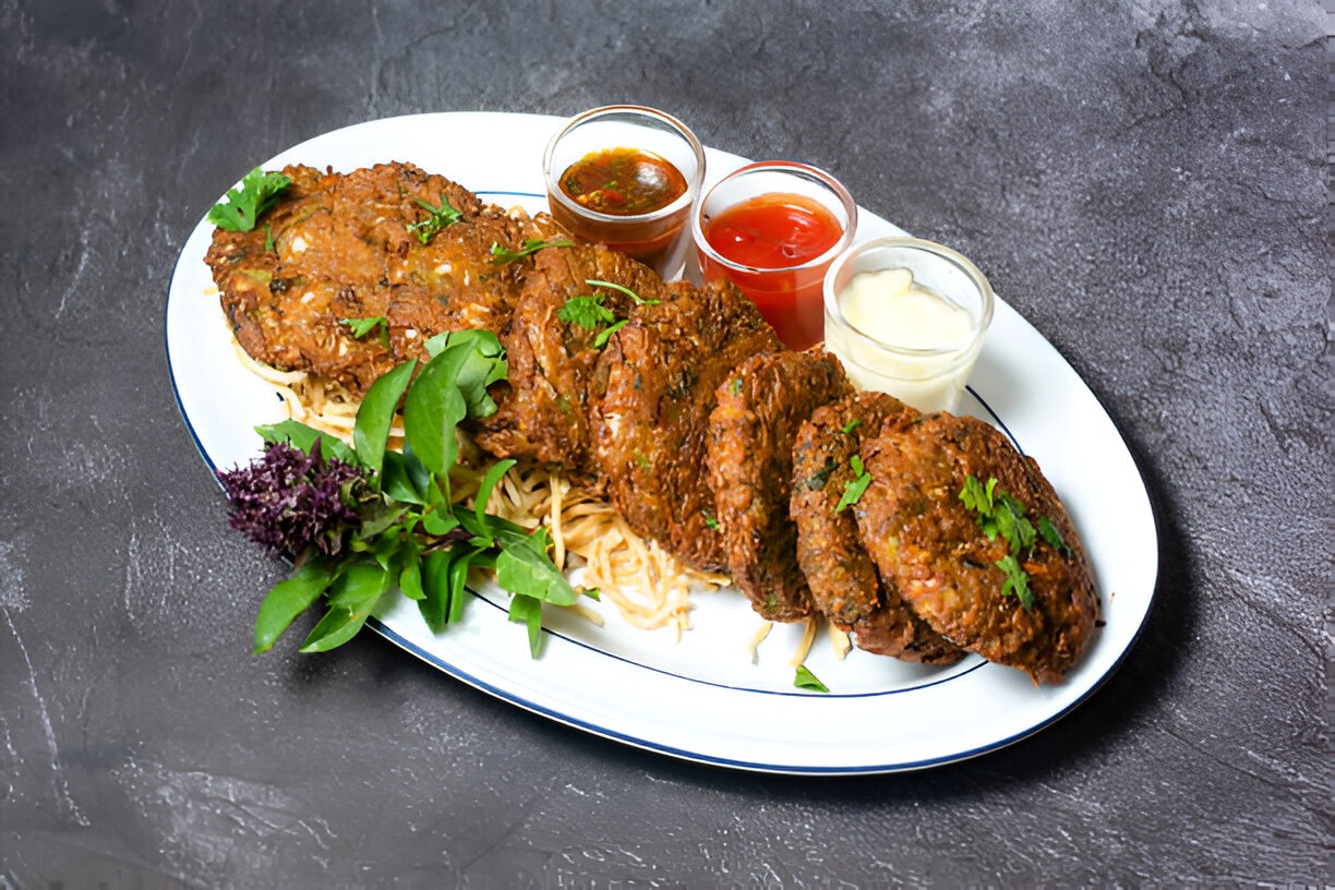 A plate of delicious kebabs served with sauces and fresh herbs.