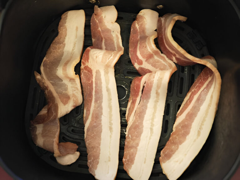Slices of bacon arranged in an air fryer basket