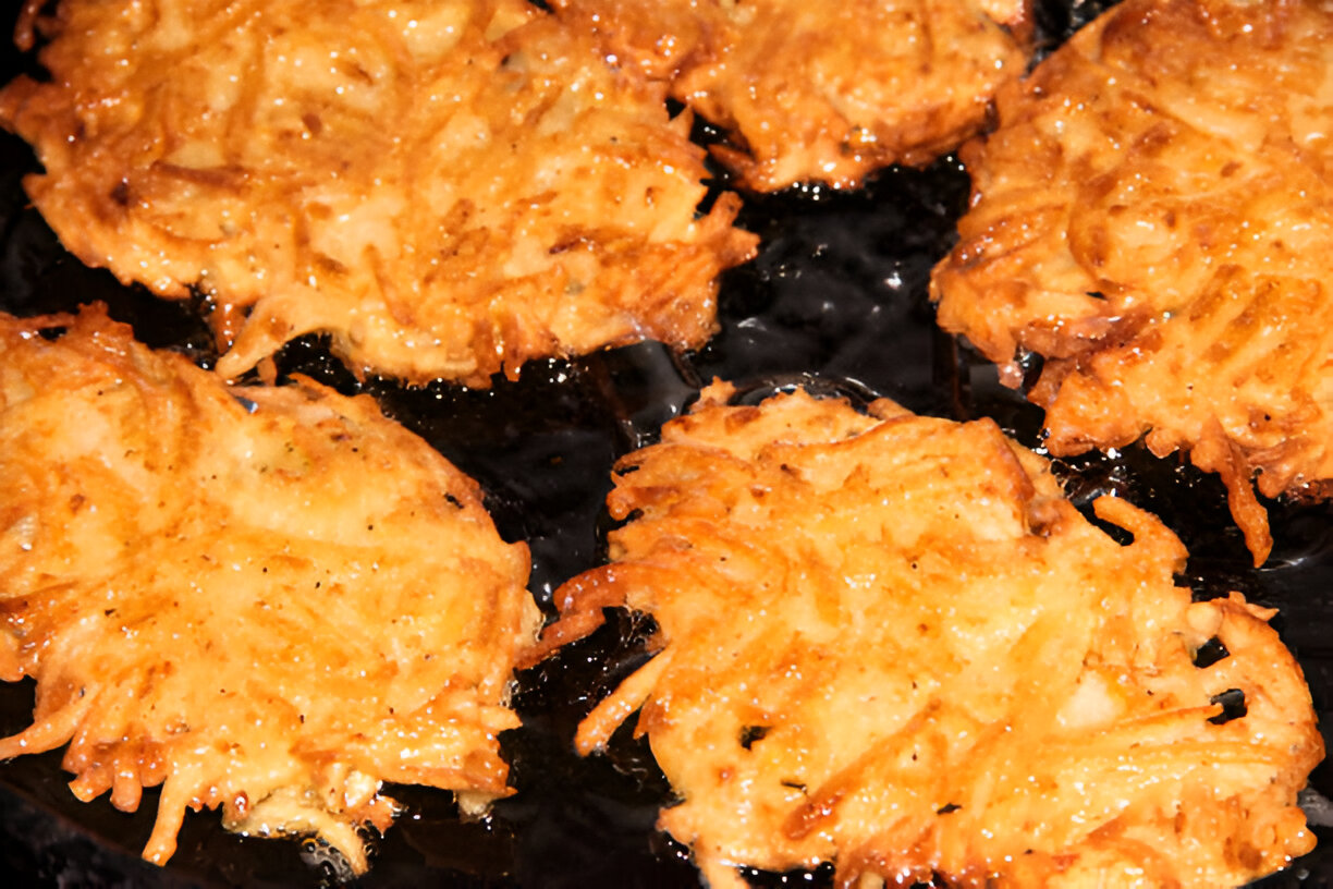 Golden brown potato latkes frying in oil.