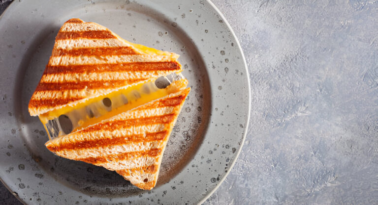 A triangular grilled cheese sandwich on a round gray plate.