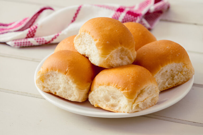 A plate of golden brown dinner rolls stacked together