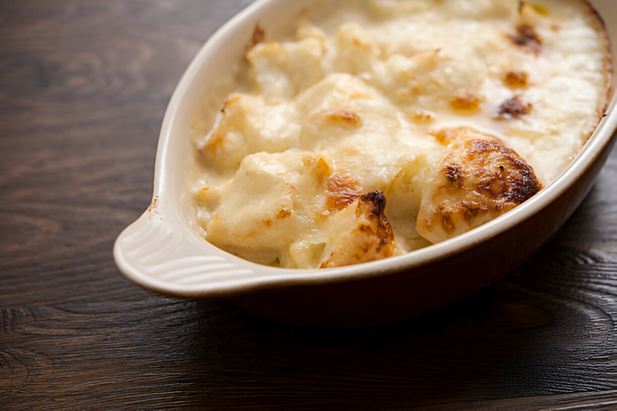 A golden and creamy baked dish in a casserole dish, featuring fluffy ingredients topped with a browned crust.