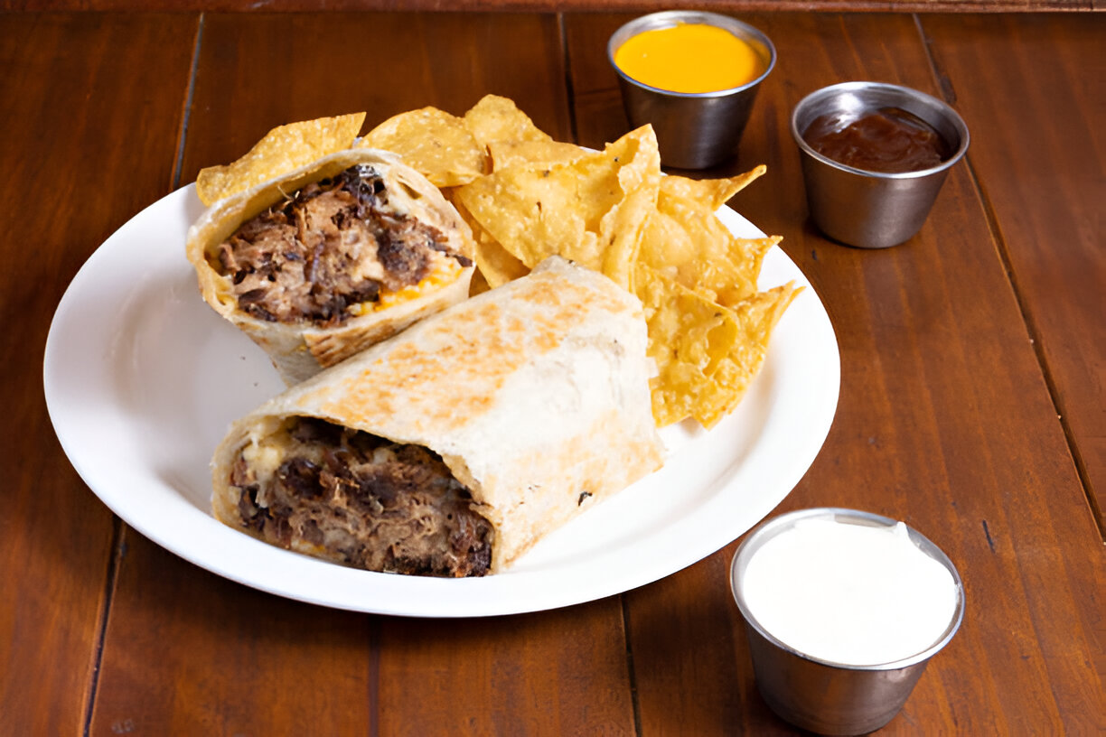 A plate with burritos, tortilla chips, and several dipping sauces.