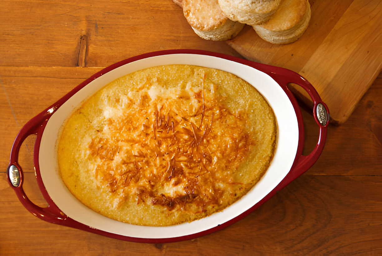 Baked casserole dish filled with golden cheesy cornbread on a wooden table