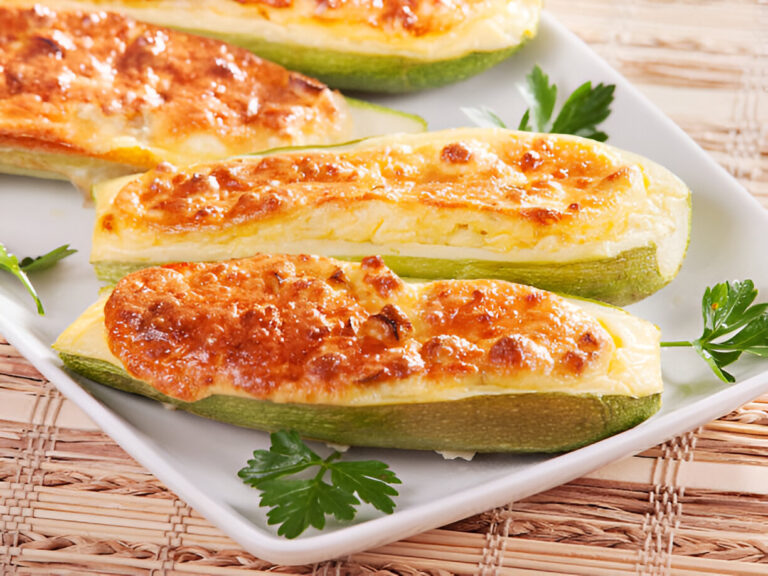 Baked stuffed zucchini boats topped with melted cheese on a white plate, garnished with parsley.