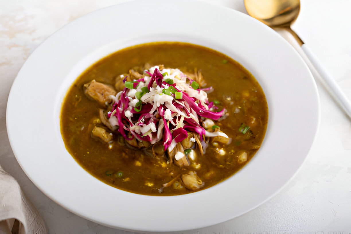 A bowl of soup with a savory broth topped with shredded cabbage and green onions.