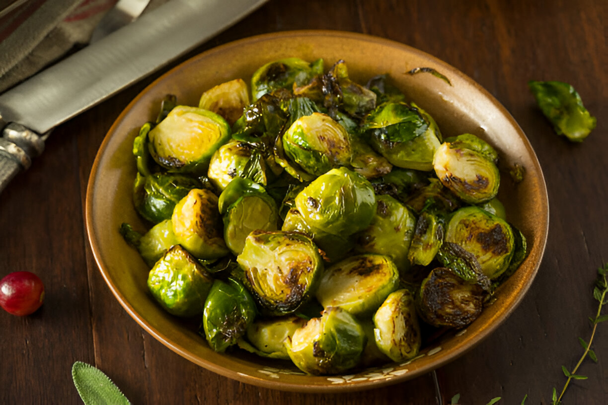 A bowl of roasted Brussels sprouts on a wooden table