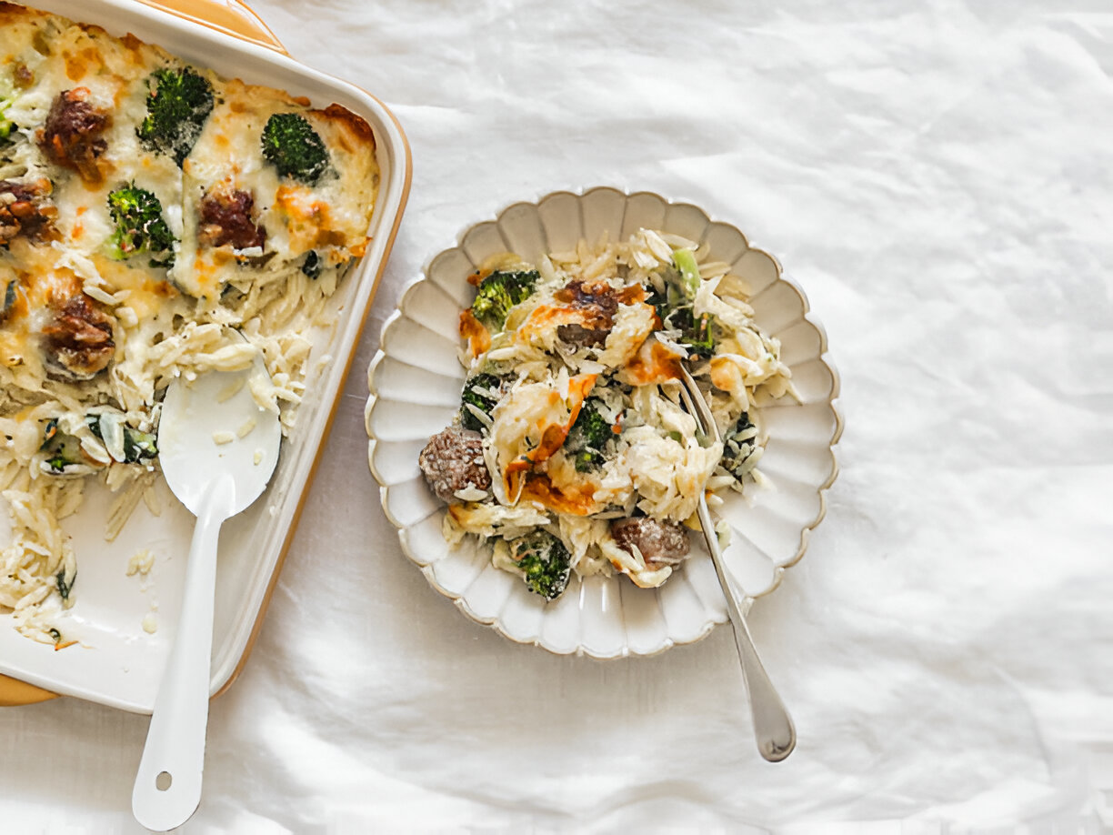 A creamy baked dish with broccoli, meats, and rice, served on a decorative plate next to the casserole dish.