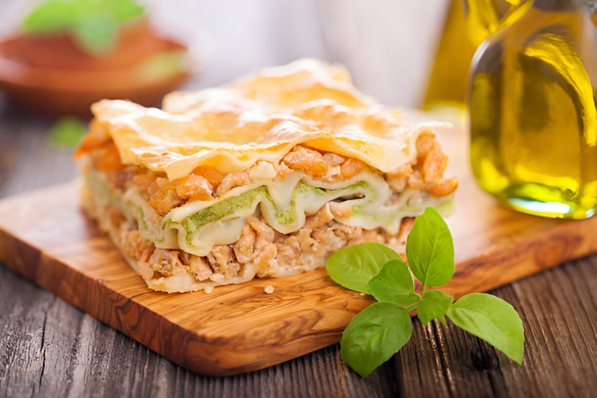 A delicious slice of homemade lasagna on a wooden cutting board, garnished with fresh basil leaves and accompanied by olive oil bottles.