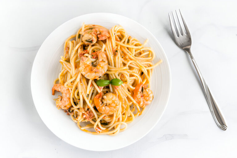 A plate of shrimp pasta with a fork on the side.