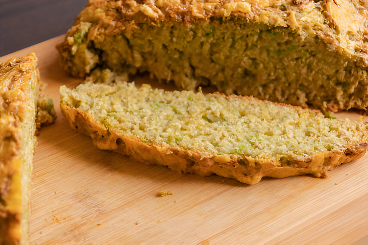 Homemade zucchini bread sliced on a wooden cutting board.